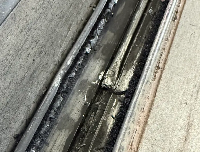 Close-up of a sliding door lower track during a track check