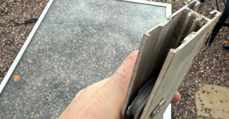 Close-up of sliding door rollers and lower track