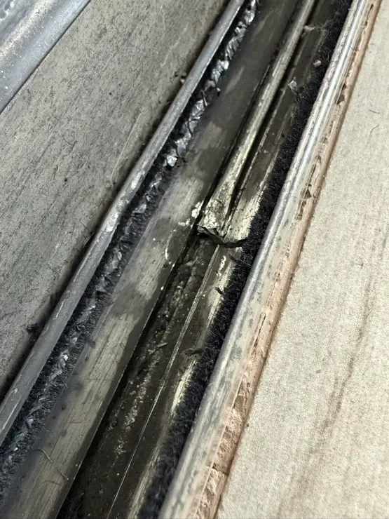 Close-up of a real worn and damaged sliding door lower track